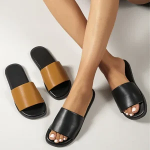 Feet wearing black slides beside brown pair