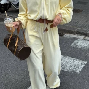 Person in pale yellow tracksuit with coffee